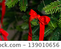 Red satin bow on evergreen branch, Christmas tree decoration close-up 139010656
