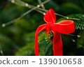 Red ribbon bow tied on evergreen branch for holiday decoration 139010658