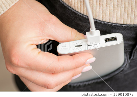 Girl putting power bank in the pocket of black jeans, close up. Modern technologies, convenient portable gadgets, charging devices concept Girl putting power bank in the pocket of black jeans, close up. Modern technologies, convenient portable gadgets, charging devices concept 139010872