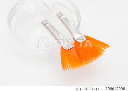 Two orange cosmetic brushes on the white background. Spa products, brushes for applying gel or facial masks 139010908