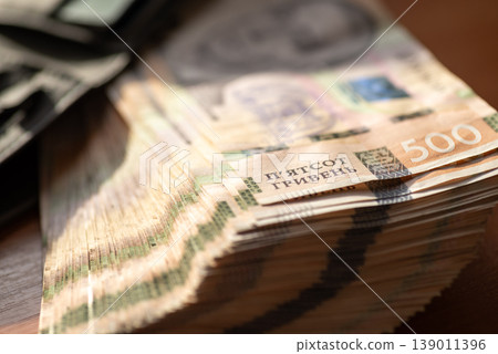 Close up of a big stack of ukrainian money on the table under the sun light. Banknotes of 500 hryvnias, concept of wealth, savings and richness Close up of a big stack of ukrainian money on the table under the sun light. Banknotes of 500 hryvnias, concept of wealth, savings and richness 139011396