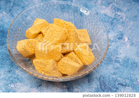 特寫鏡頭展現了堆放在藍色背景上的黃豆粉麻糬(裹著烤黃豆粉的年糕)。 特寫鏡頭展現了堆放在藍色背景上的黃豆粉麻糬(裹著烤黃豆粉的年糕)。 139012828