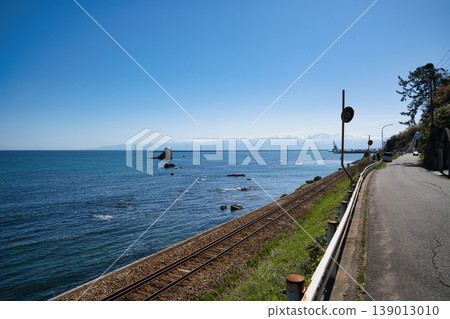 The breathtaking scenery of Amaharashi Coast under a clear blue sky, and the Himi Line railway tracks running along the coast. The breathtaking scenery of Amaharashi Coast under a clear blue sky, and the Himi Line railway tracks running along the coast. 139013010