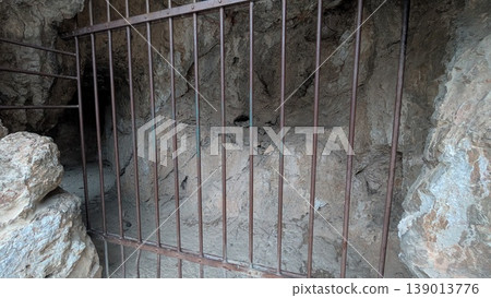 A cave in the mountain that is said to have been an ancient prison seen through the iron fence A cave in the mountain that is said to have been an ancient prison seen through the iron fence 139013776