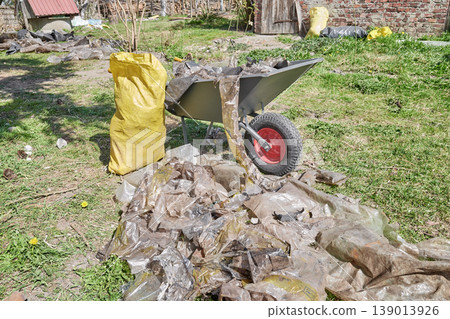 A garden wheelbarrow overflowing with discarded plastic wrap and bags. A garden wheelbarrow overflowing with discarded plastic wrap and bags. 139013926