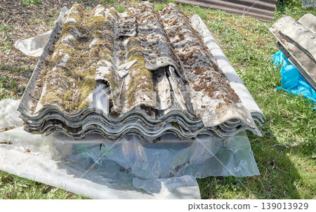 Old asbestos roof tiles stacked on a pallet. Old asbestos roof tiles stacked on a pallet. 139013929