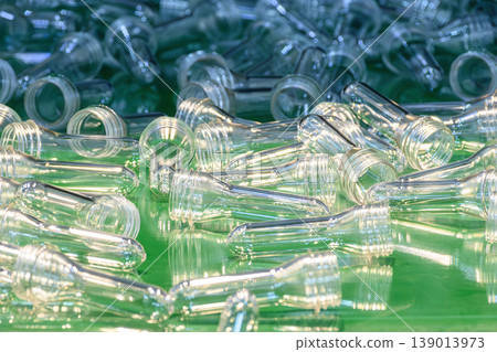 Close-up of clear PET preforms on an automated conveyor belt system from a plastic injection machine. Close-up of clear PET preforms on an automated conveyor belt system from a plastic injection machine. 139013973