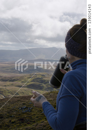 Woman hydrating during a highland mountain hike Woman hydrating during a highland mountain hike 139014143