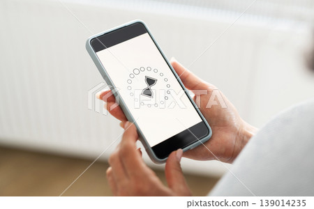 Girl Holding Smartphone With Rotating Hourglass 139014235