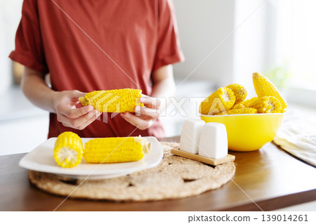 Young Girl Eating Boiling Corn Cobs For Eating 139014261