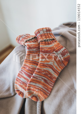Hand knitted cosy socks on a blanket. Concept for handmade and hygge slow life. Hand knitted cosy socks on a blanket. Concept for handmade and hygge slow life. 139014352
