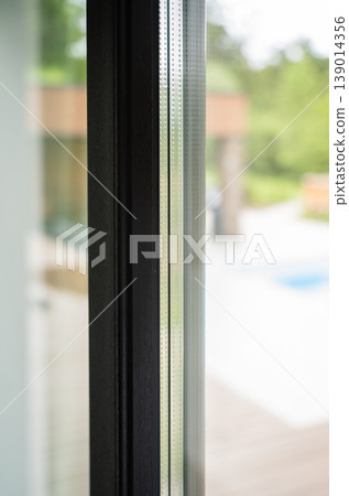Close up of modern architectural window frame with double pane glass providing insulation and soundproofing Close up of modern architectural window frame with double pane glass providing insulation and soundproofing 139014356