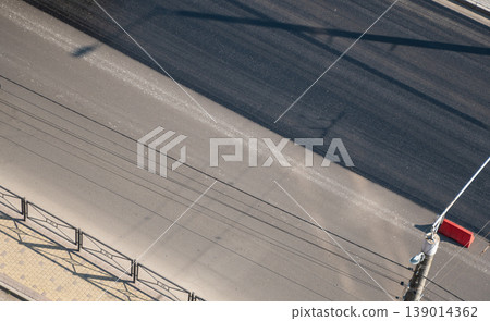 Diagonal view of an asphalt road and sidewalk with contrasting light and shadow, urban street texture 139014362