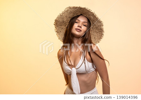 Young woman confidently posing in straw hat and white bikini while ready for summer vacation Young woman confidently posing in straw hat and white bikini while ready for summer vacation 139014396
