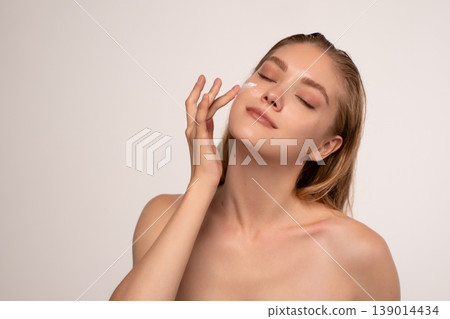 Woman applying facial cream for healthy skin, nurturing a natural glow and beauty routine with spa wellness Woman applying facial cream for healthy skin, nurturing a natural glow and beauty routine with spa wellness 139014434