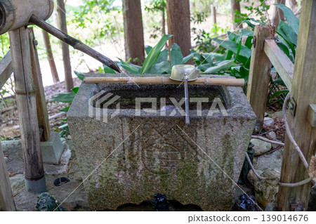 The tranquil scenery of the purification fountain at Tamano Ontake Shrine, adorned with fresh greenery. 139014676