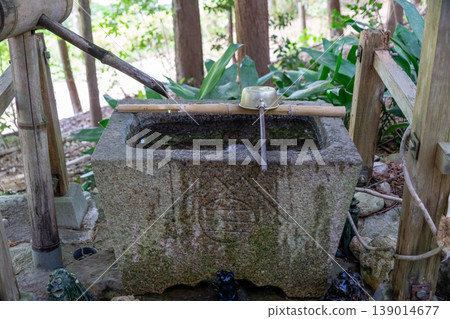 The tranquil scenery of the purification fountain at Tamano Ontake Shrine, adorned with fresh greenery. 139014677