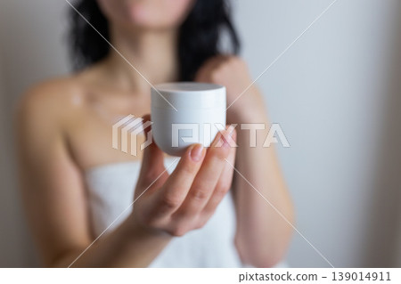 Woman holding cosmetic cream jar after shower, skincare routine and moisturizing beauty treatment concept Woman holding cosmetic cream jar after shower, skincare routine and moisturizing beauty treatment concept 139014911