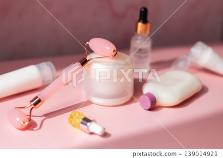Skincare beauty products set with facial roller, cream jar, serum dropper and cosmetic bottles on pink background, beauty routine concept Skincare beauty products set with facial roller, cream jar, serum dropper and cosmetic bottles on pink background, beauty routine concept 139014921