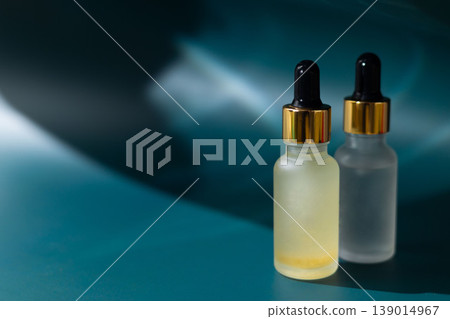 Frosted glass cosmetic dropper bottle on natural stone with dark blue background, skincare serum packaging mockup, minimal beauty product concept 139014967