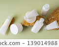 Flat lay of minimal skincare cosmetic bottles, tubes and cream jar on natural stones with soft green background 139014988