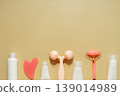 Flat lay skincare beauty routine with cosmetic bottles, serum dropper, facial roller, massage tool and towel on warm pastel background 139014989