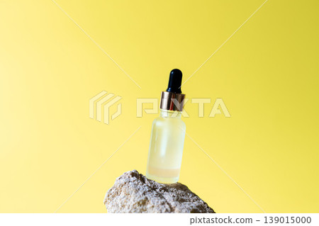 Cosmetic serum dropper bottle on natural stone with bright yellow background, skincare oil beauty product concept 139015000
