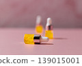 Yellow cosmetic serum dropper bottles on pink background, skincare oil texture with pipette, beauty product concept 139015001