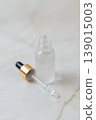 Glass cosmetic droppers with transparent serum on mirror surface, skincare essence drops and reflection, beauty treatment concept, minimalist cosmetic product background. 139015003