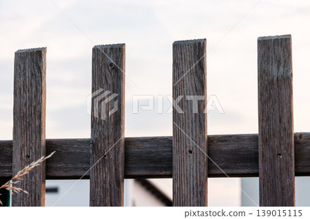 Weathered wooden fence boards against bright sky close up. Rustic outdoor background with copy space and minimal composition. Weathered wooden fence boards against bright sky close up. Rustic outdoor background with copy space and minimal composition. 139015115