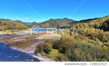[Aerial View] A panoramic view of the clear waters of the Ishikari River and the Daisetsu Lake! The magnificent nature of Hokkaido in autumn. 139015419