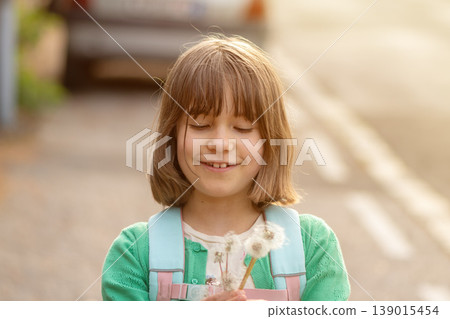 Child 8 years old standing on road with dandelion flowers smiling in soft light Child 8 years old standing on road with dandelion flowers smiling in soft light 139015454