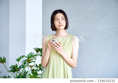 一位年輕女子正陷入沉思，目光緊盯著她的智慧型手機。 139016232