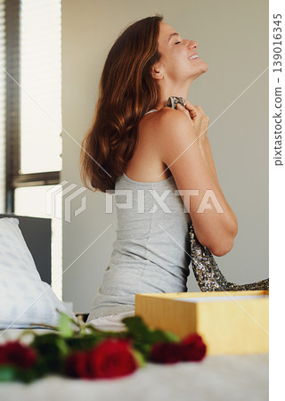Woman, bedroom and box for gift, dress and happy with roses for birthday, valentines day or event. Girl, clothes and fashion with cardboard package, present and flowers on bed with thinking in home 139016345
