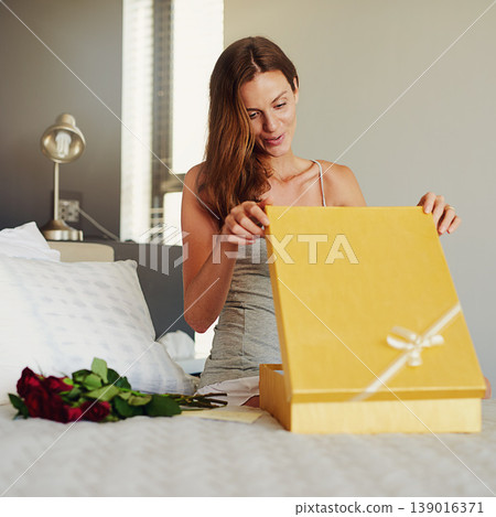 Woman, bedroom and open box with roses, present and happy for surprise on birthday, valentines day and event. Girl, cardboard package and gift with smile on bed with thinking in home for celebration Woman, bedroom and open box with roses, present and happy for surprise on birthday, valentines day and event. Girl, cardboard package and gift with smile on bed with thinking in home for celebration 139016371