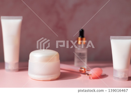 Skincare beauty products set with facial roller, cream jar, serum dropper and cosmetic bottles on pink background, beauty routine concept Skincare beauty products set with facial roller, cream jar, serum dropper and cosmetic bottles on pink background, beauty routine concept 139016467
