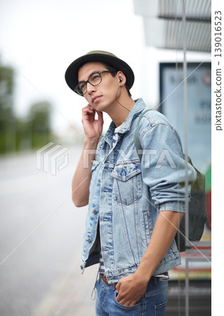 Man, earphones and listening to music, bus stop and commute or travel, adventure and journey in town. Male person, streaming radio and audio or song, podcast and outdoors for public transport by road Man, earphones and listening to music, bus stop and commute or travel, adventure and journey in town. Male person, streaming radio and audio or song, podcast and outdoors for public transport by road 139016523