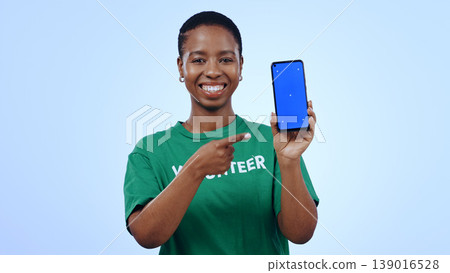 Woman, volunteering and point at phone with green screen in portrait for mockup on blue background in studio. Black person, happy or smile for internet, cellular or network for homepage on mobile app 139016528