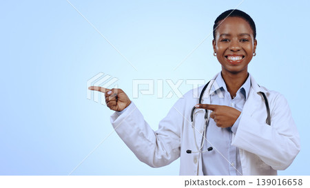 Doctor, portrait and pointing for presentation in studio with smile, announcement or advertising space. Black woman, face and happy for marketing, showing deal or discount with hand or joy on mockup Doctor, portrait and pointing for presentation in studio with smile, announcement or advertising space. Black woman, face and happy for marketing, showing deal or discount with hand or joy on mockup 139016658
