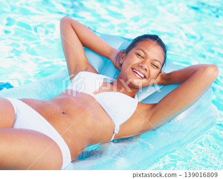 Woman, bikini and smile on lilo in pool with summer sunshine, vacation or float with healthy body. Girl, swimwear and happy on water, thinking or outdoor for holiday, freedom or nature in Indonesia Woman, bikini and smile on lilo in pool with summer sunshine, vacation or float with healthy body. Girl, swimwear and happy on water, thinking or outdoor for holiday, freedom or nature in Indonesia 139016809