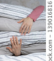 woman holds stack of pillows with her hands while sitting on the bed. rest and restful sleep.  139016816