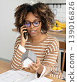 female architect or realtor holds mock up of house in her hands, talks on phone with client. 139016826