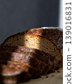 sliced brown bread lies on wooden board. ray of light. Sourdough rye bread with crispy crust.  139016831