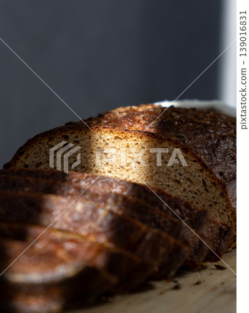 sliced brown bread lies on wooden board. ray of light. Sourdough rye bread with crispy crust.  139016831