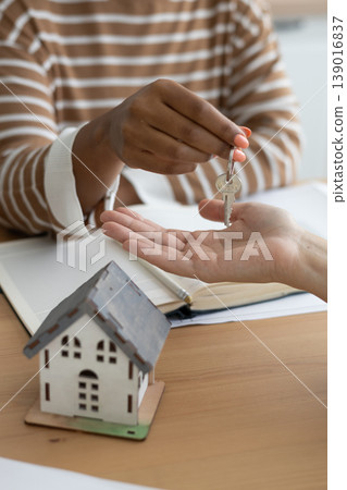 Close-up of happy woman realtor or property owner handing over key to house. Close-up of happy woman realtor or property owner handing over key to house. 139016837