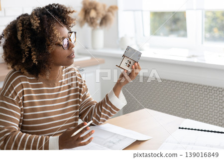 female architect or realtor holds mock up of house in her hands, deals with planning. female architect or realtor holds mock up of house in her hands, deals with planning. 139016849