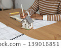 close up view of house layout that stands on table. female architect is working on creating. 139016851