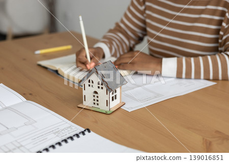 close up view of house layout that stands on table. female architect is working on creating. close up view of house layout that stands on table. female architect is working on creating. 139016851