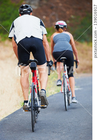 Back, road and couple cycling in nature for cardio, fitness and training on bicycle together. Outdoor, people and exercise on bike for fun, workout and travel in countryside adventure or journey Back, road and couple cycling in nature for cardio, fitness and training on bicycle together. Outdoor, people and exercise on bike for fun, workout and travel in countryside adventure or journey 139016917