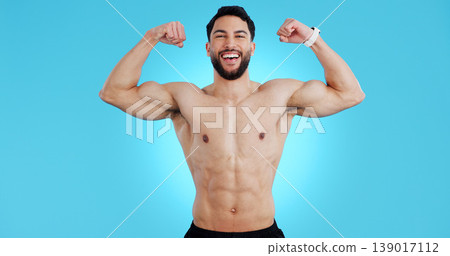 Happy man, portrait and muscle flex of bodybuilder in fitness isolated against a blue studio background. Male person, athlete or model smile showing strength, power or results for workout on mockup 139017112
